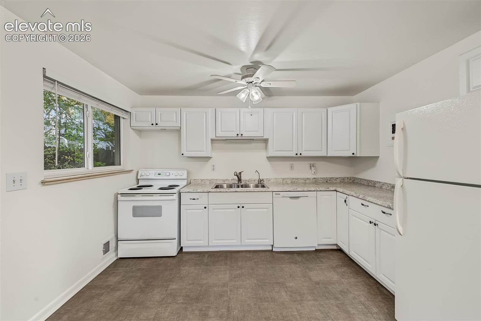 Kitchen featuring white cabinetry, stone-finish countertops, dual-basin stainless steel sink, built-in dishwasher, and ceiling-mounted fan