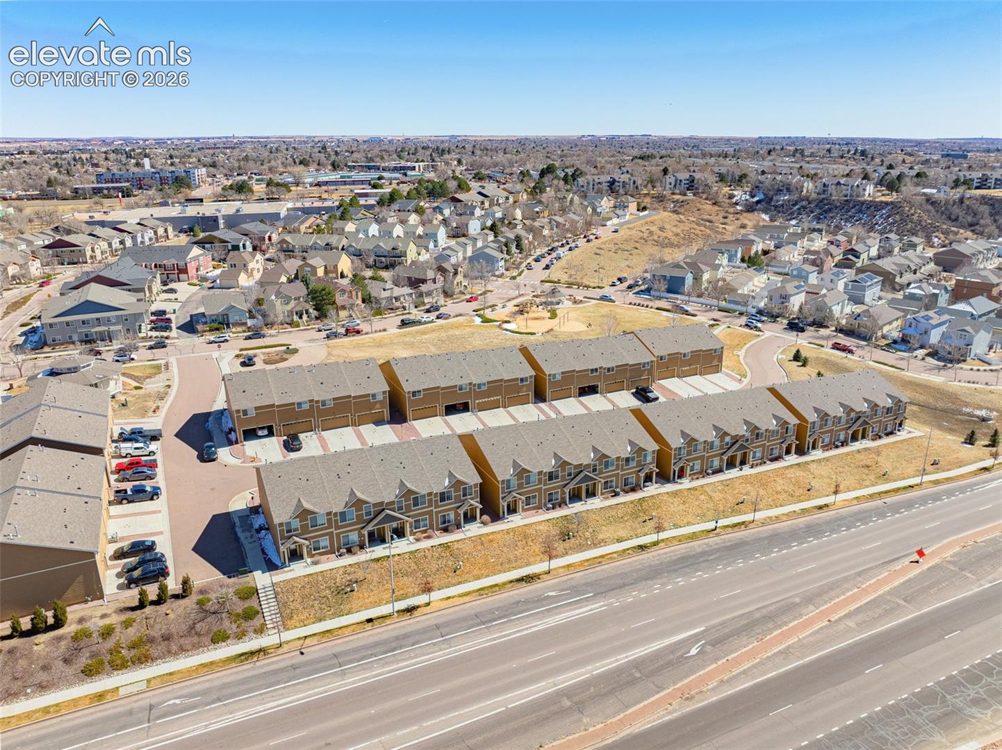 Townhome community featuring multi-story units, attached garages, and a paved street