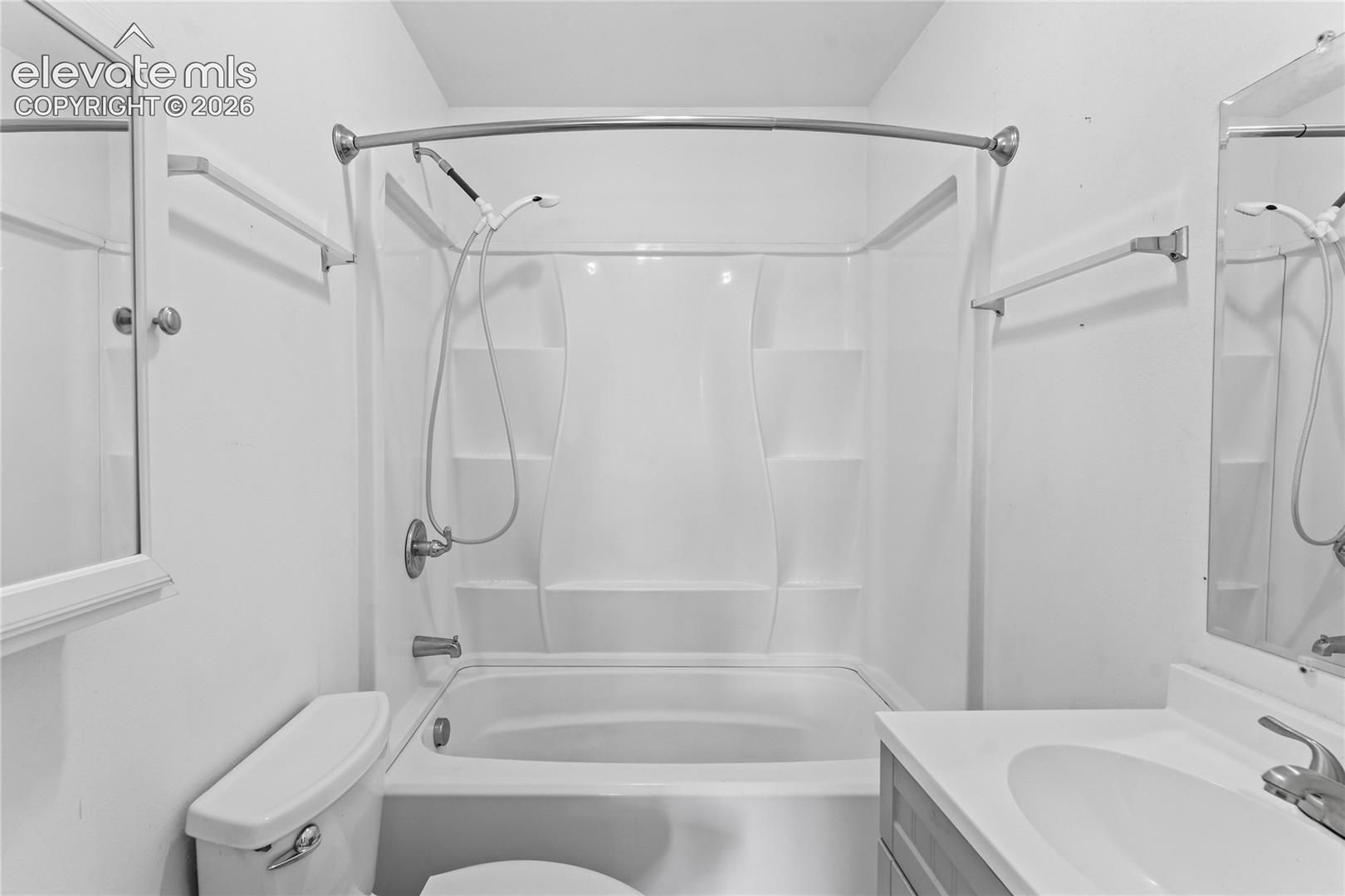 Bathroom featuring a white tub-shower combination with built-in shelving, chrome fixtures, and a curved shower rod