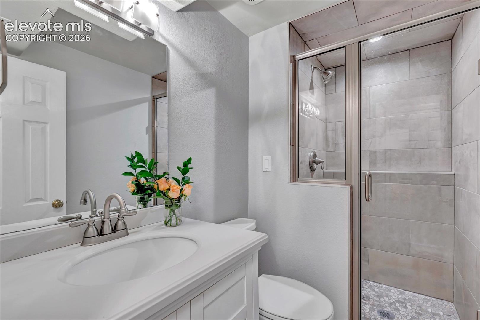 Bathroom featuring a white vanity with integrated sink, brushed nickel faucet, and overhead lighting