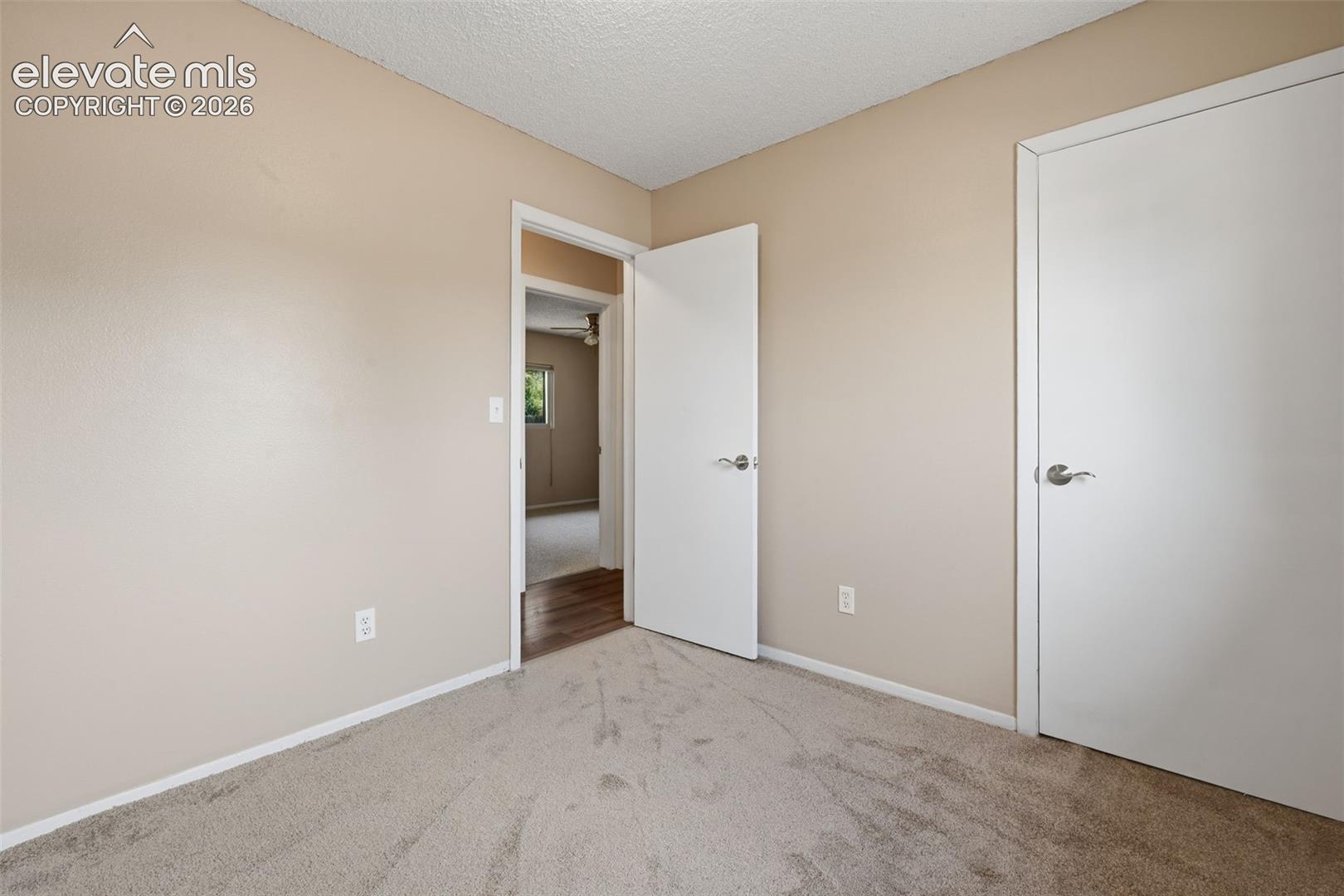Neutral tone wall paint, textured ceiling, and neutral tone carpeting
