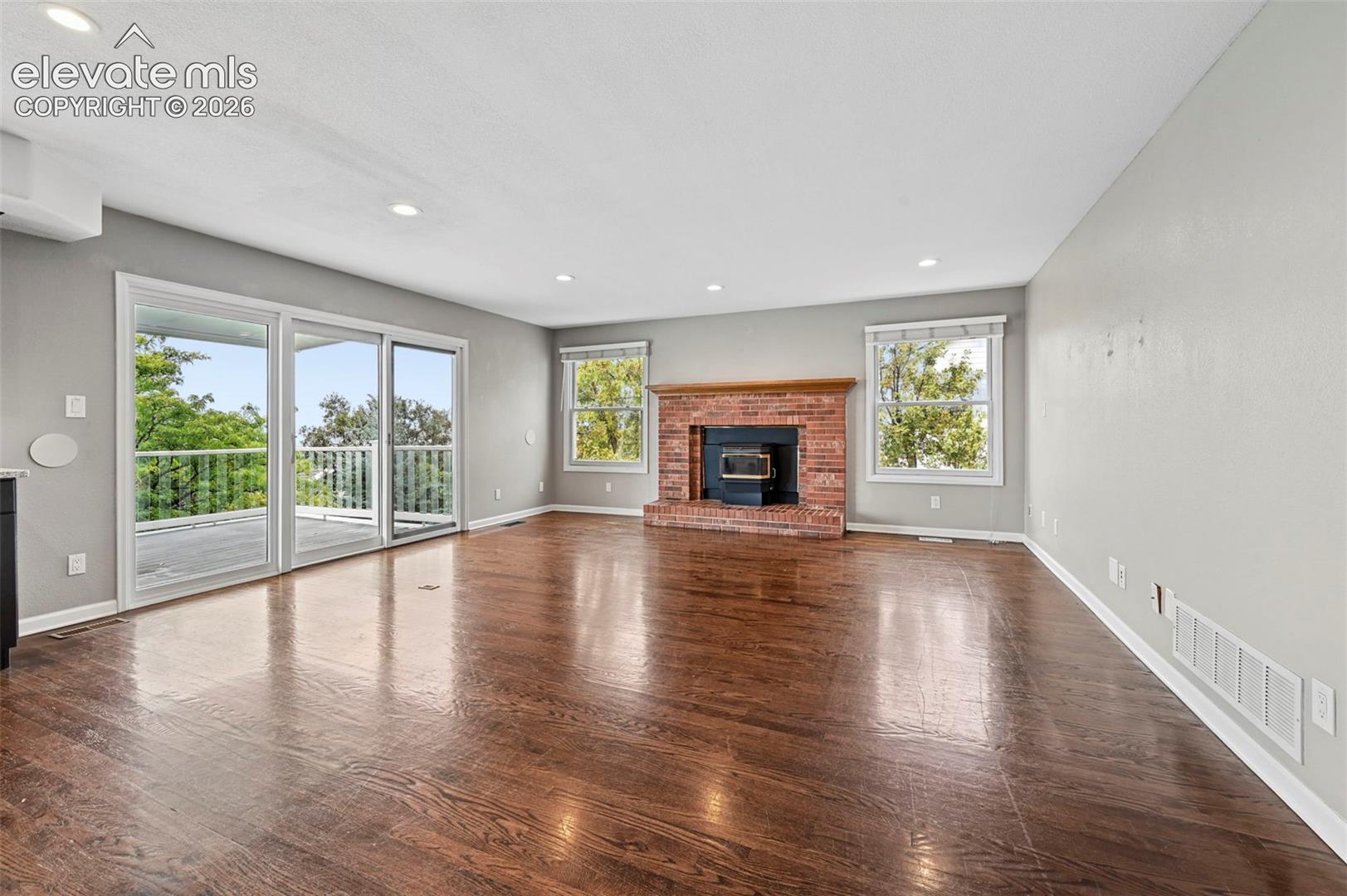 Unstaged Family room with brick fireplace/pellet stove, adjacent to kitchen - walkout to covered large upper deck
