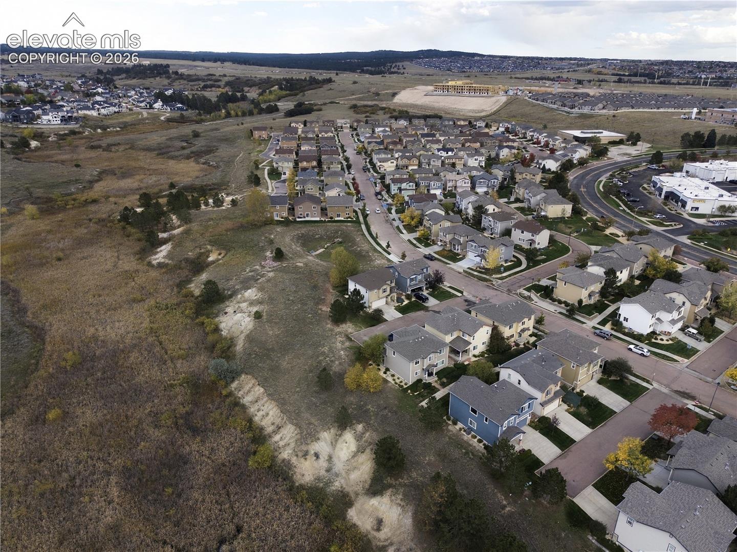 Aerial perspective of a residential community featuring asphalt roadways, planned subdivision lots, and proximity to expansive natural terrain