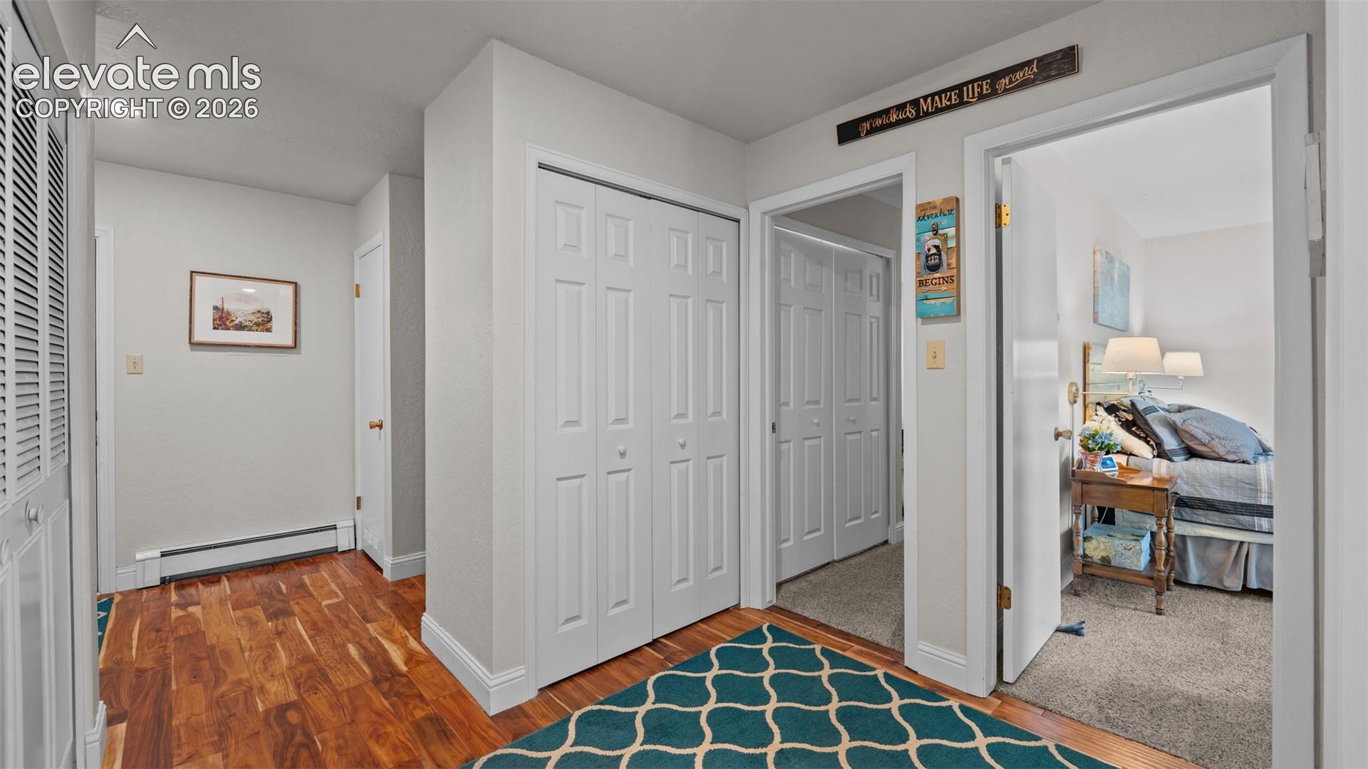Hallway featuring wood-finish flooring, recessed lighting, and multiple bi-fold door closets