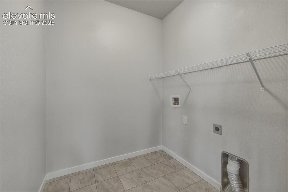 Utility space with tile flooring and built in shelves. 