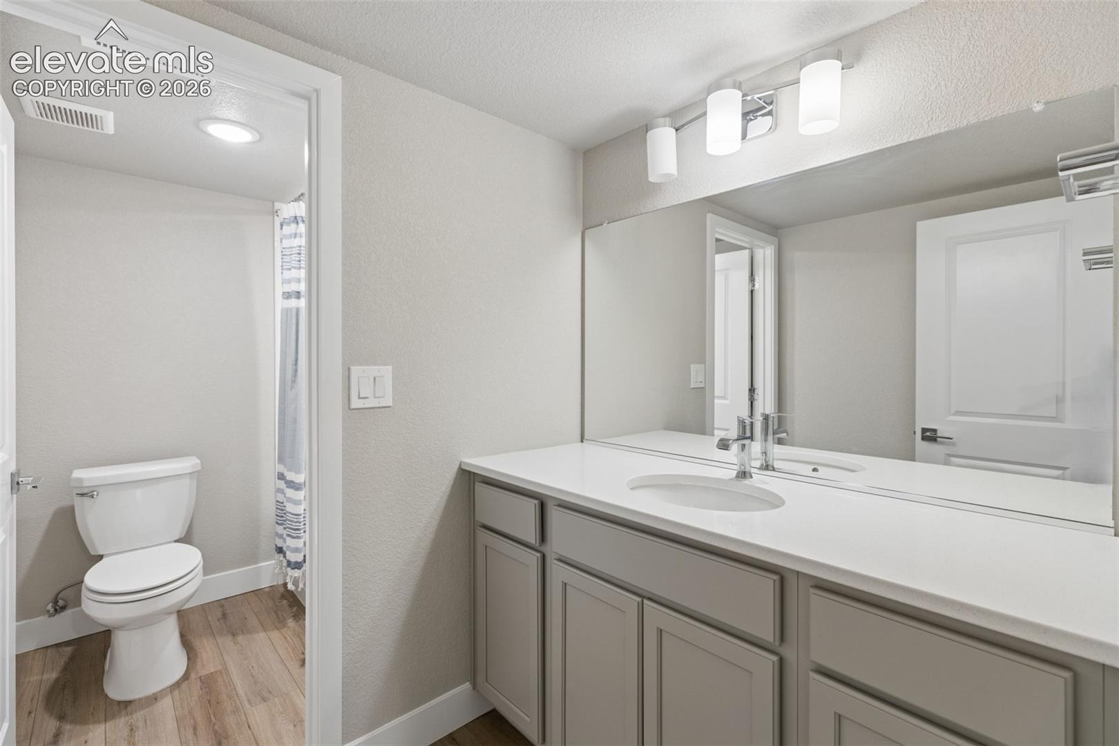 Vanity featuring light gray cabinetry, a white countertop with an integrated oval sink, and a full-width mirror