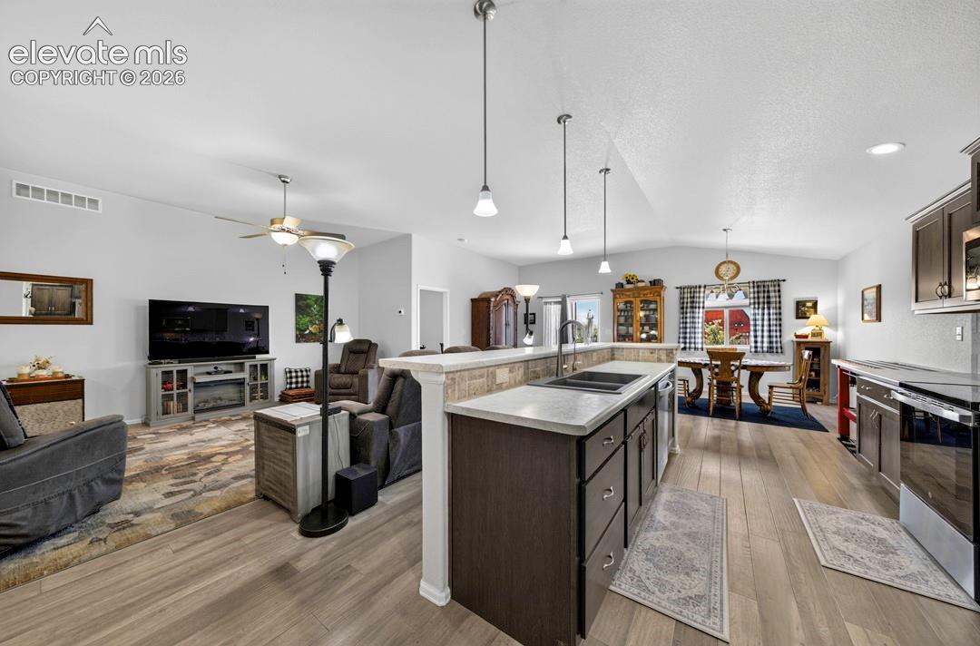 Open-concept living space featuring wood-finish flooring, vaulted ceilings, and recessed lighting