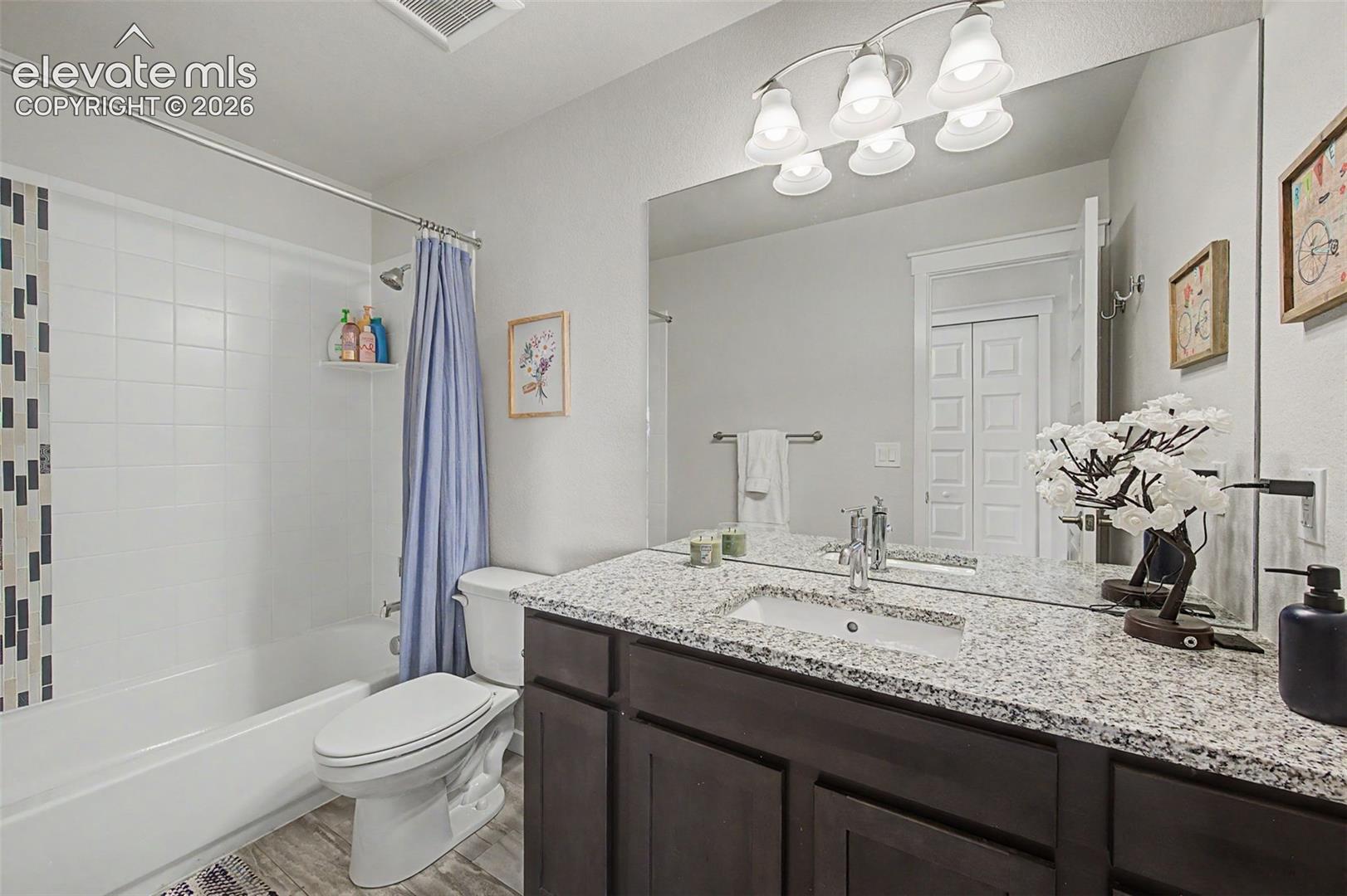 The upper level full hall bath features a granite vanity.