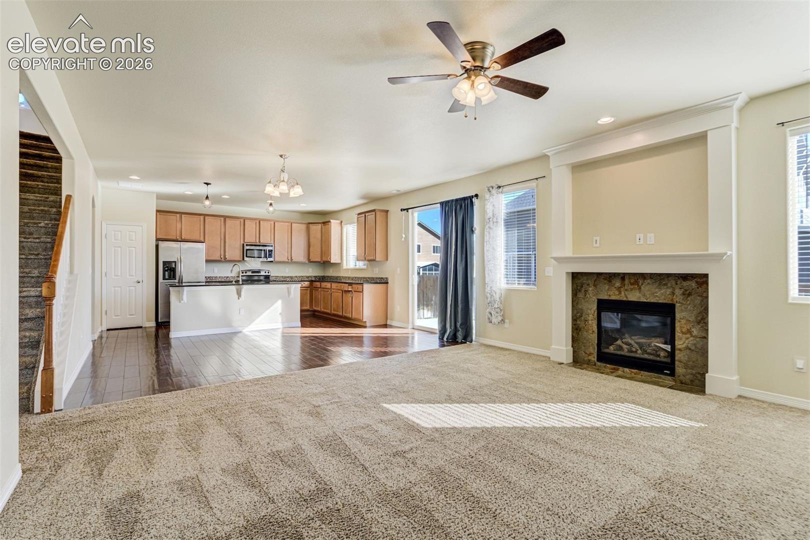 Spacious living area with a built-in fireplace, ceiling fan, and sliding glass door