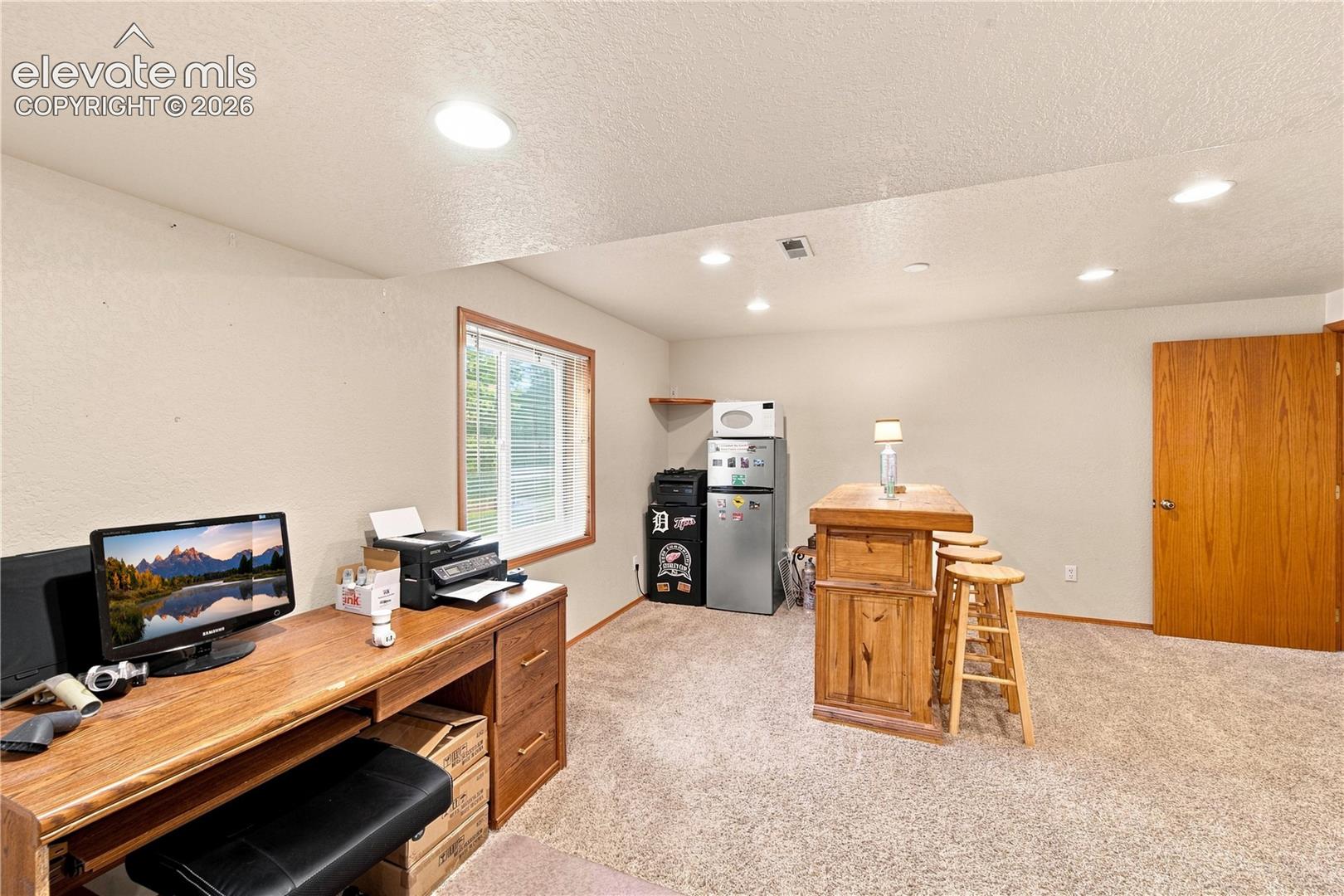 Recessed lighting, wood-finish desk with drawers, natural light window, wood-finish bar, and carpeted flooring