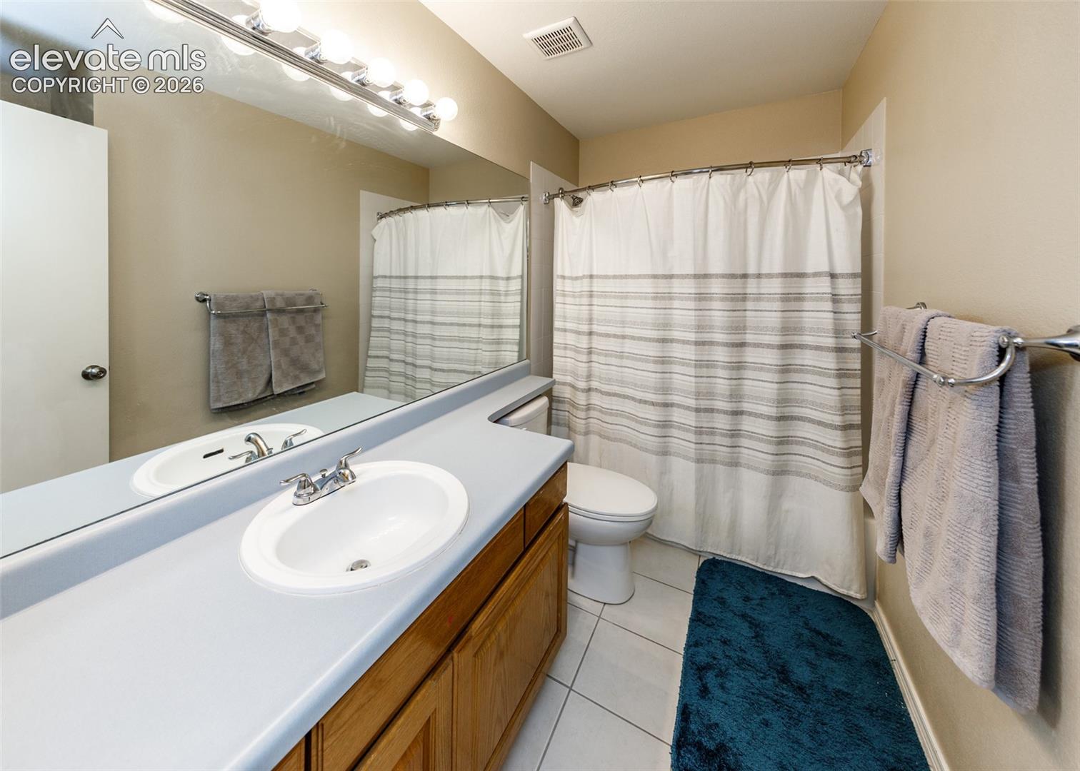 Wood-finish vanity with an integrated basin, chrome faucet, and expansive wall mirror