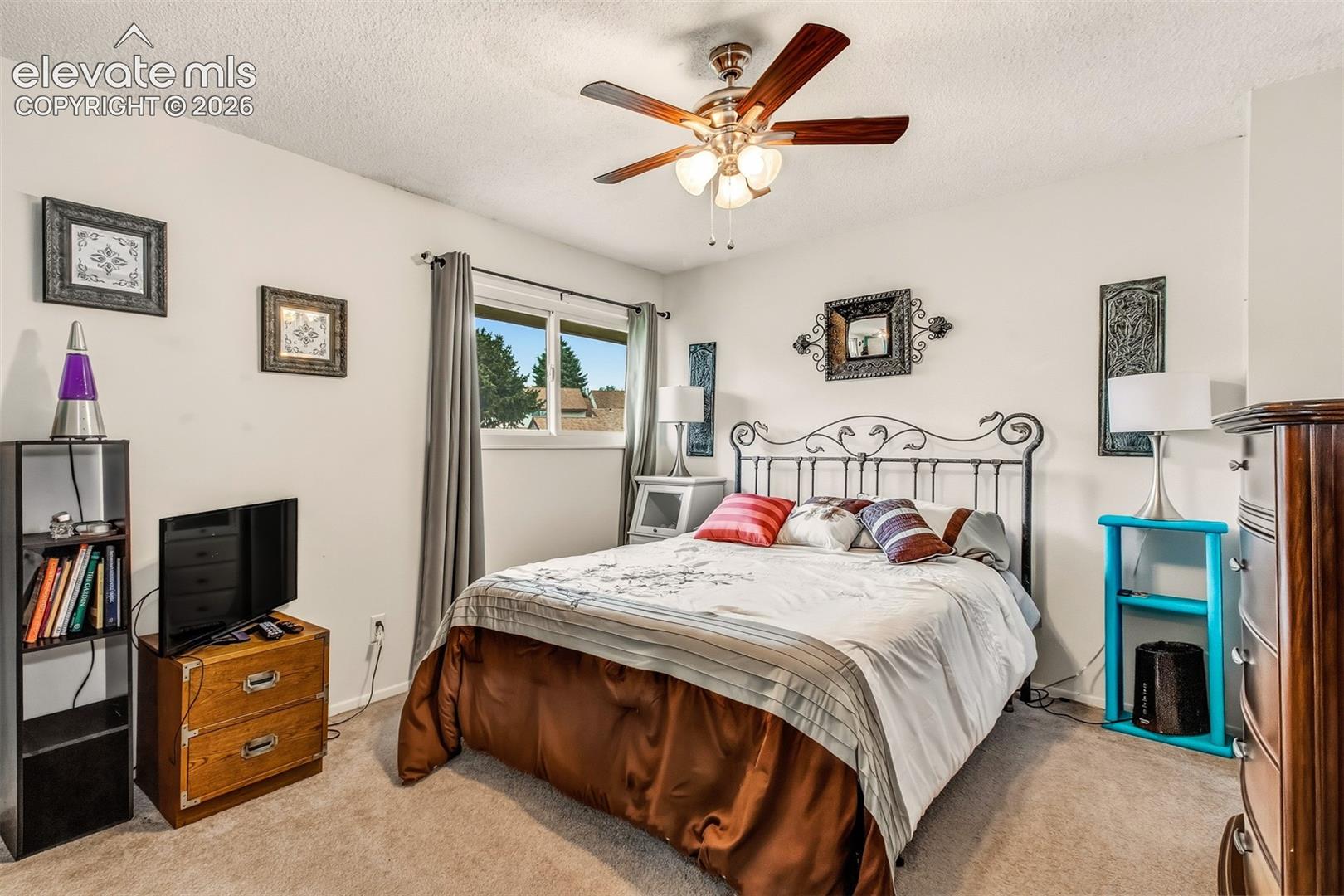 Room featuring neutral-toned carpeting, a center-mounted ceiling fan with integrated lighting, and a sliding window