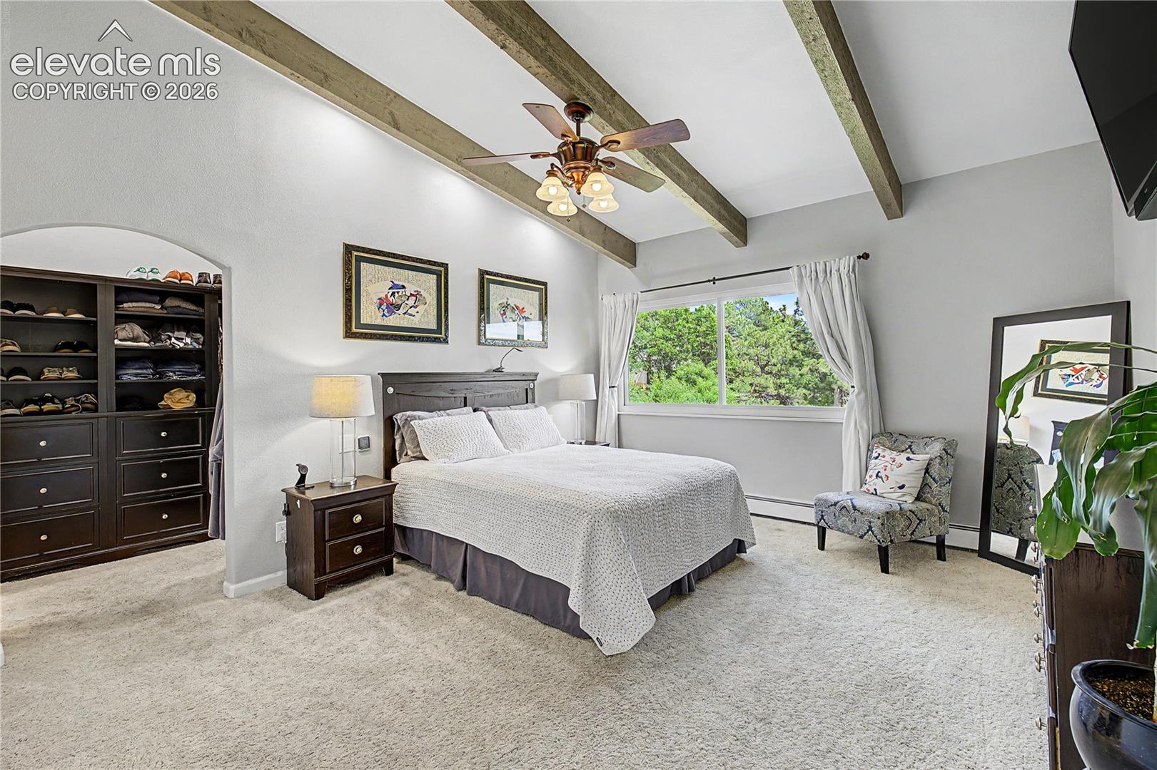 A built-in arched closet nook adds a custom touch to a primary suite that feels both spacious and serene.