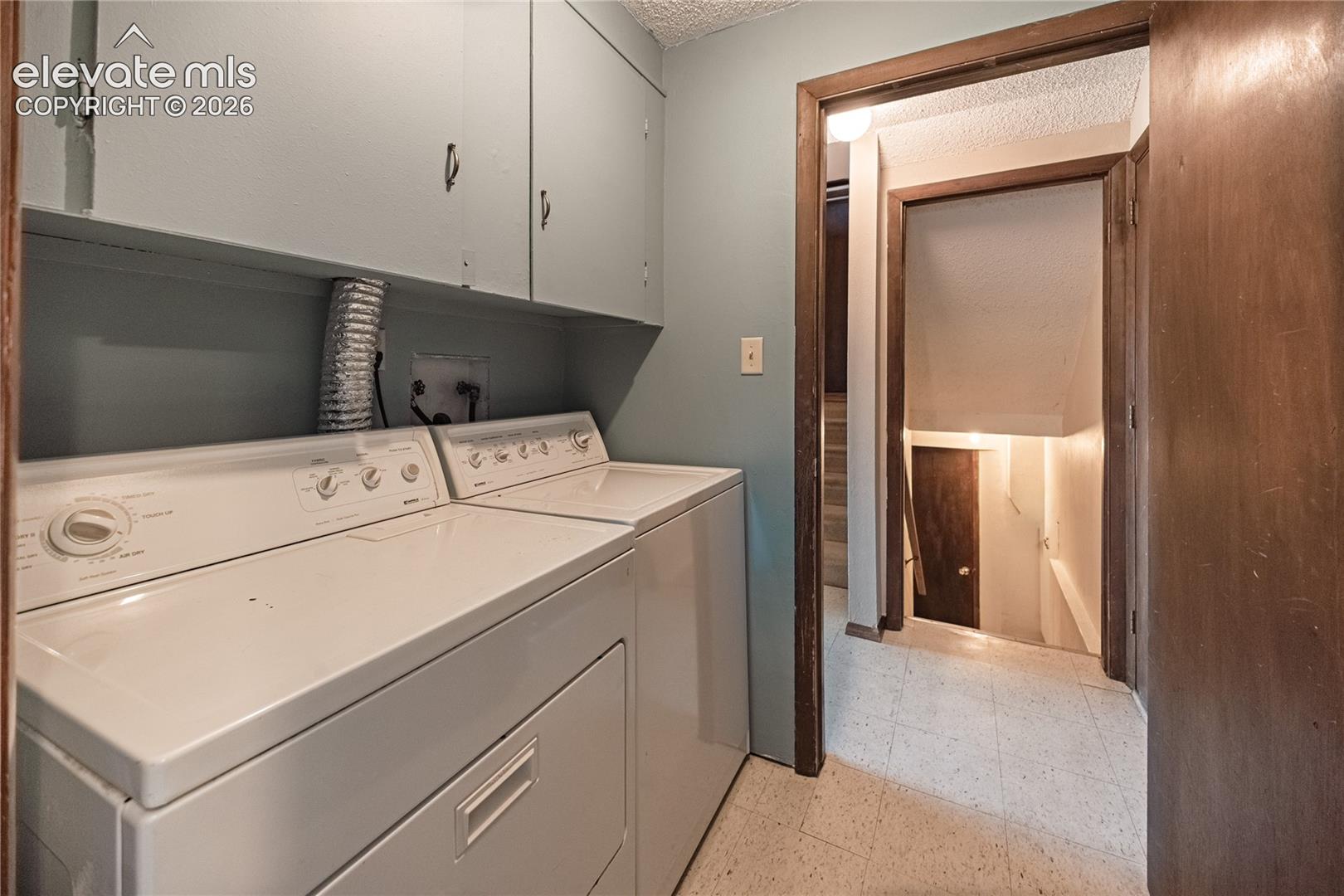 Utility area featuring wall-mounted cabinetry, dedicated laundry hookups, and hard-surface flooring
