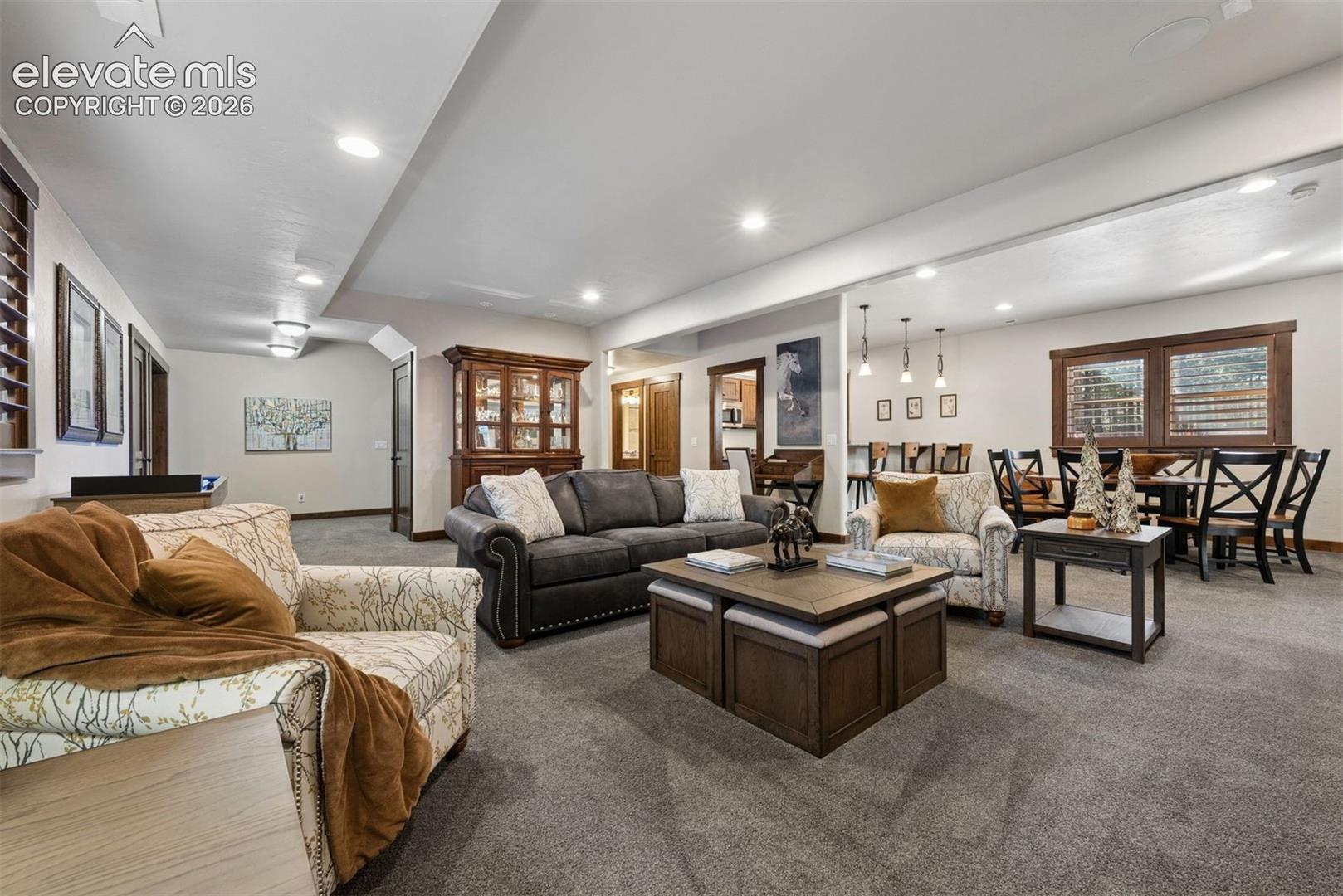 Open-concept interior featuring recessed lighting, neutral wall tones, wall-to-wall carpeting, and natural wood-trim window casings