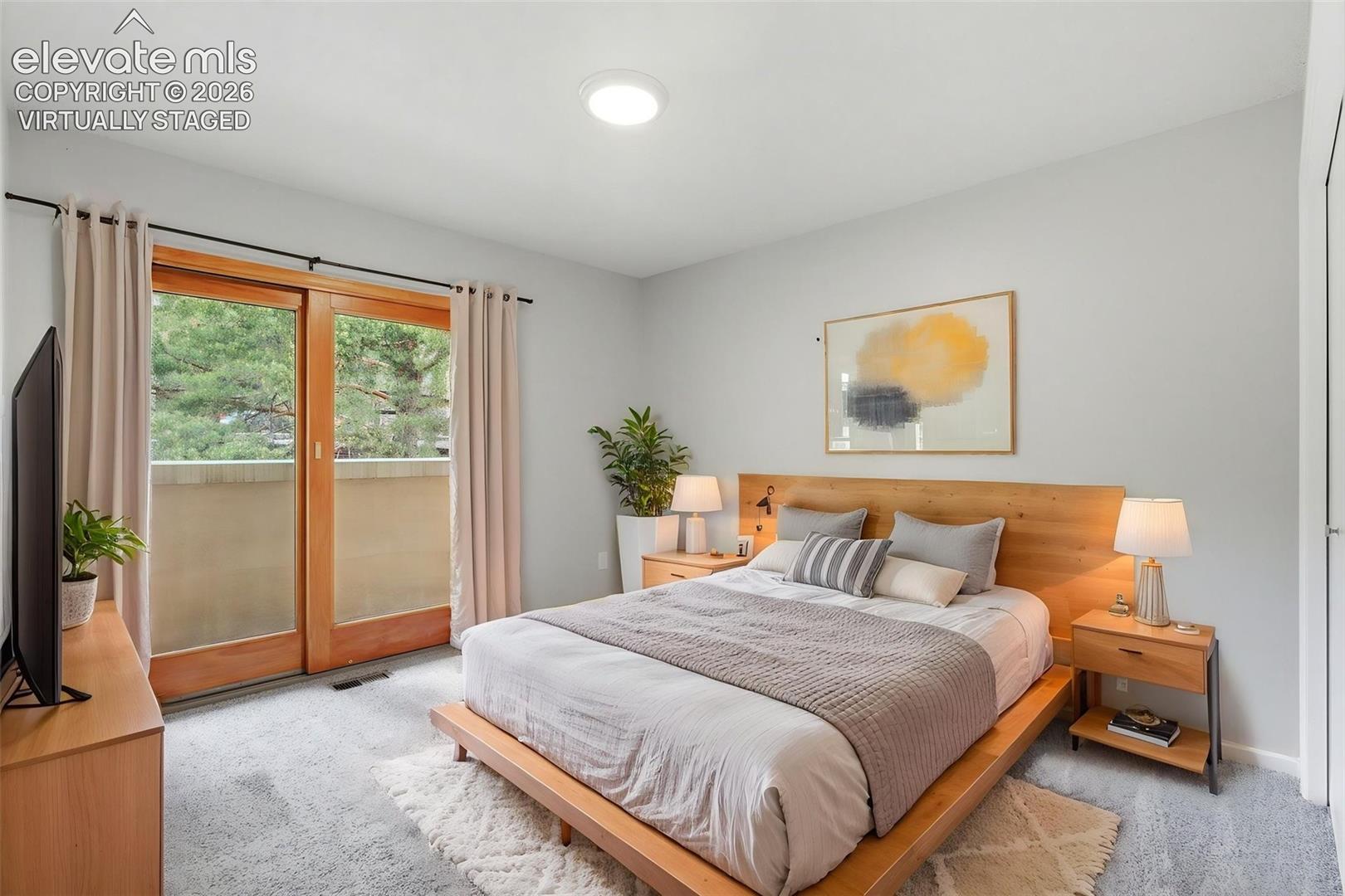 Virtually Staged - Sliding glass doors opening to an exterior balcony, light gray wall finishes, recessed ceiling lighting, and soft carpet flooring