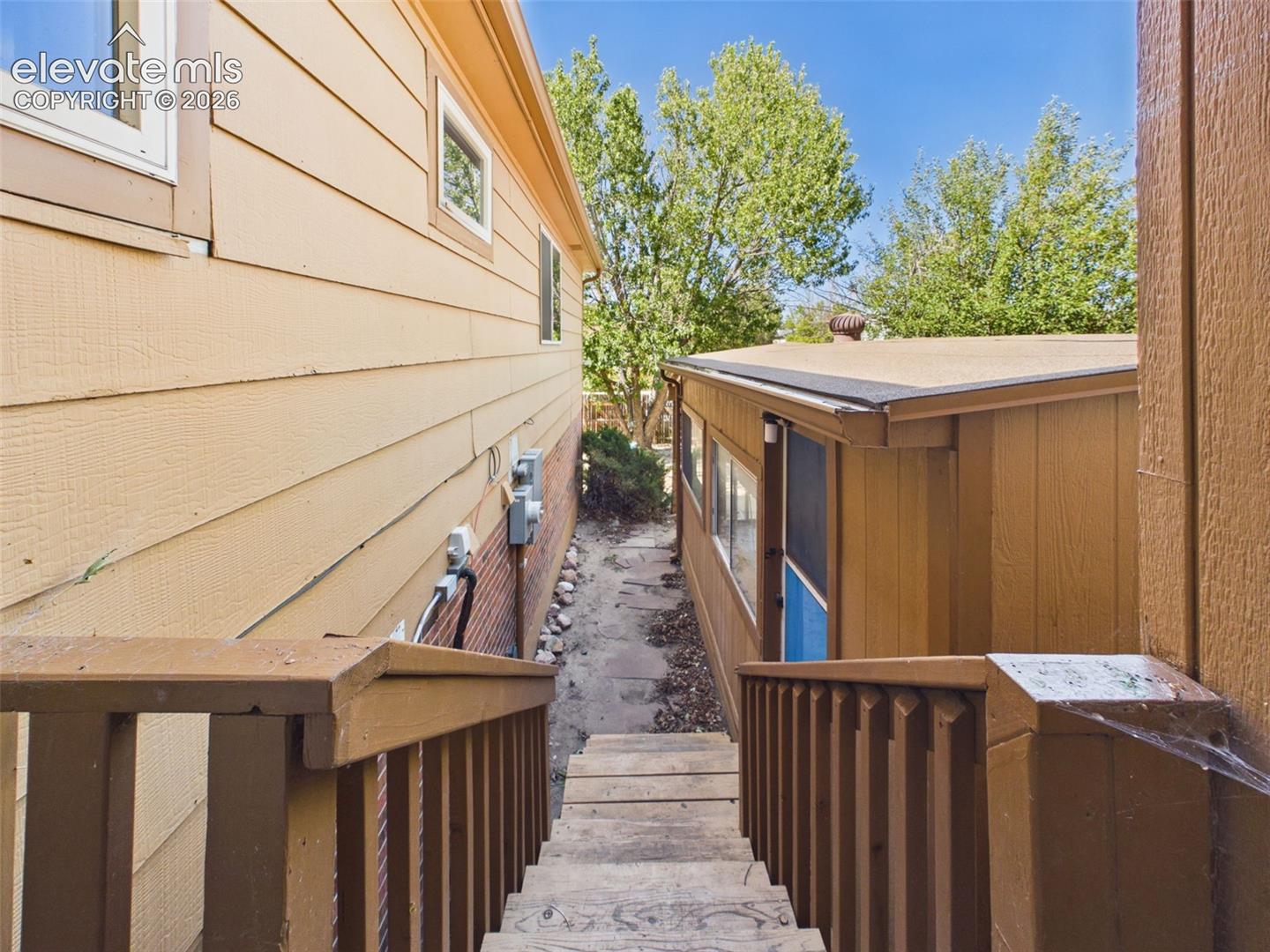 Exterior stairs and a stone pathway provide access between levels and connect the home with the surrounding outdoor areas.