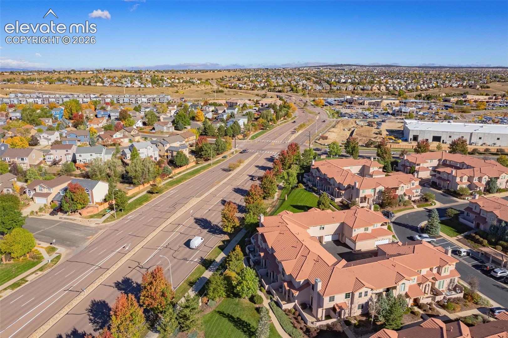 Aerial perspective of a multi-unit residential complex featuring terracotta-tiled roofs, stucco exterior finish, and paved driveway access within a suburban setting