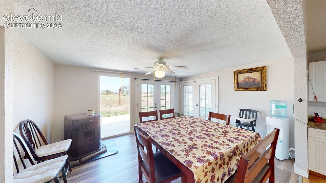 Built-in stove with hearth pad, wood-finish flooring, ceiling fan, and multiple French doors