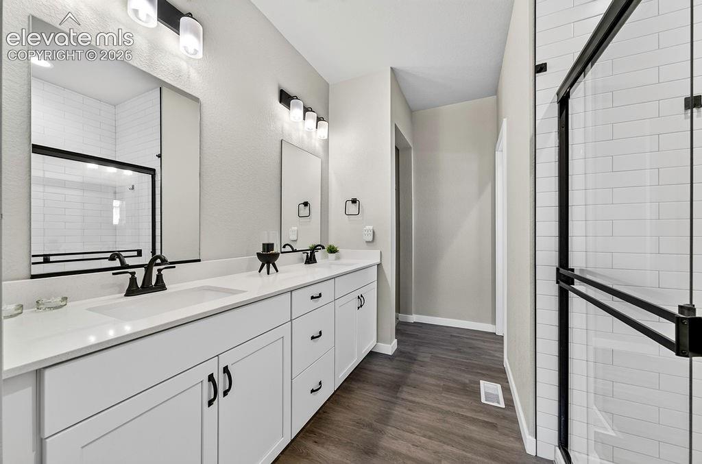 Bathroom featuring a dual vanity with white cabinetry, white countertops, and matte black hardware