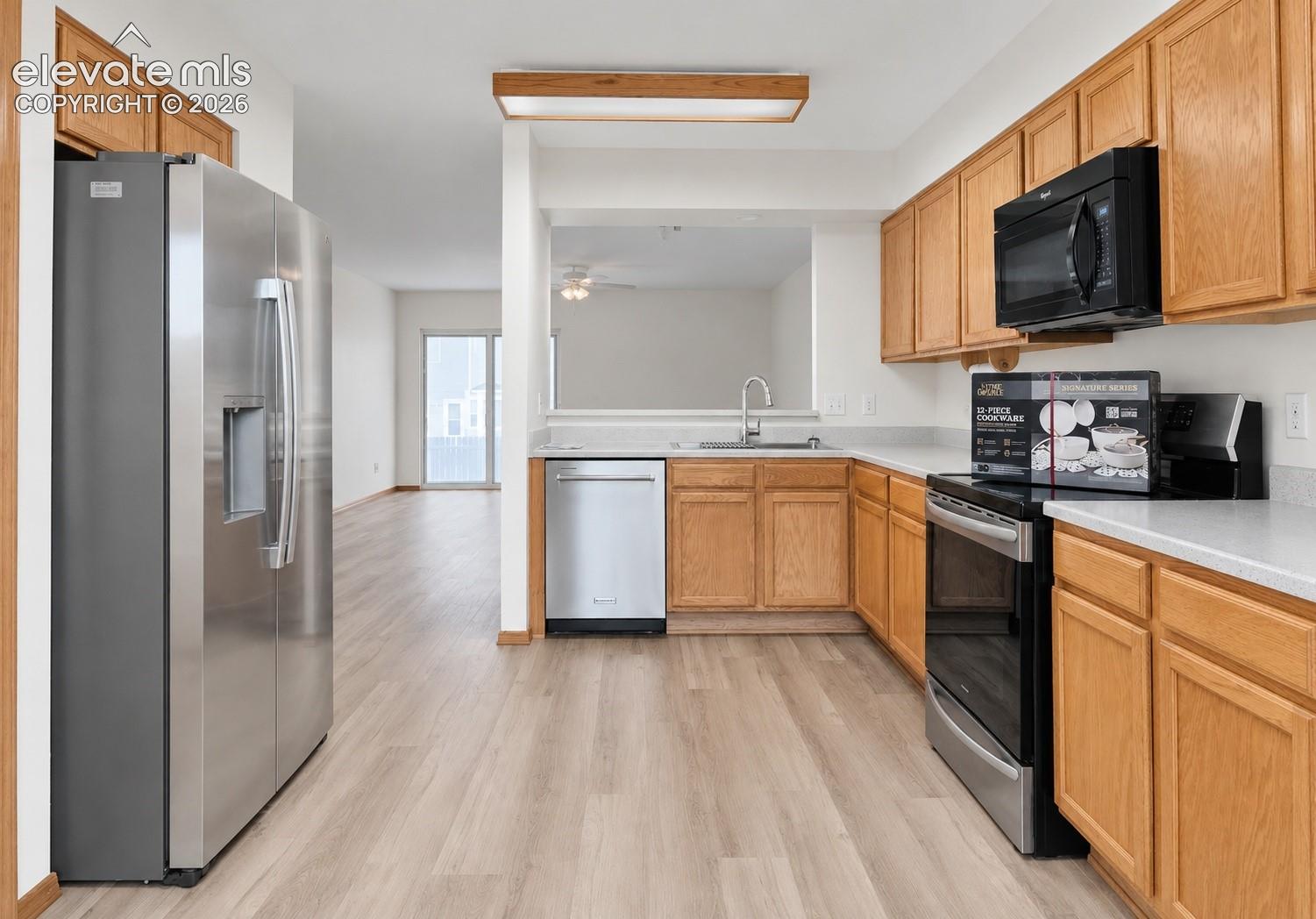 Kitchen featuring light-finish cabinetry, wood-finish flooring, solid-surface countertops, and stainless steel appliances