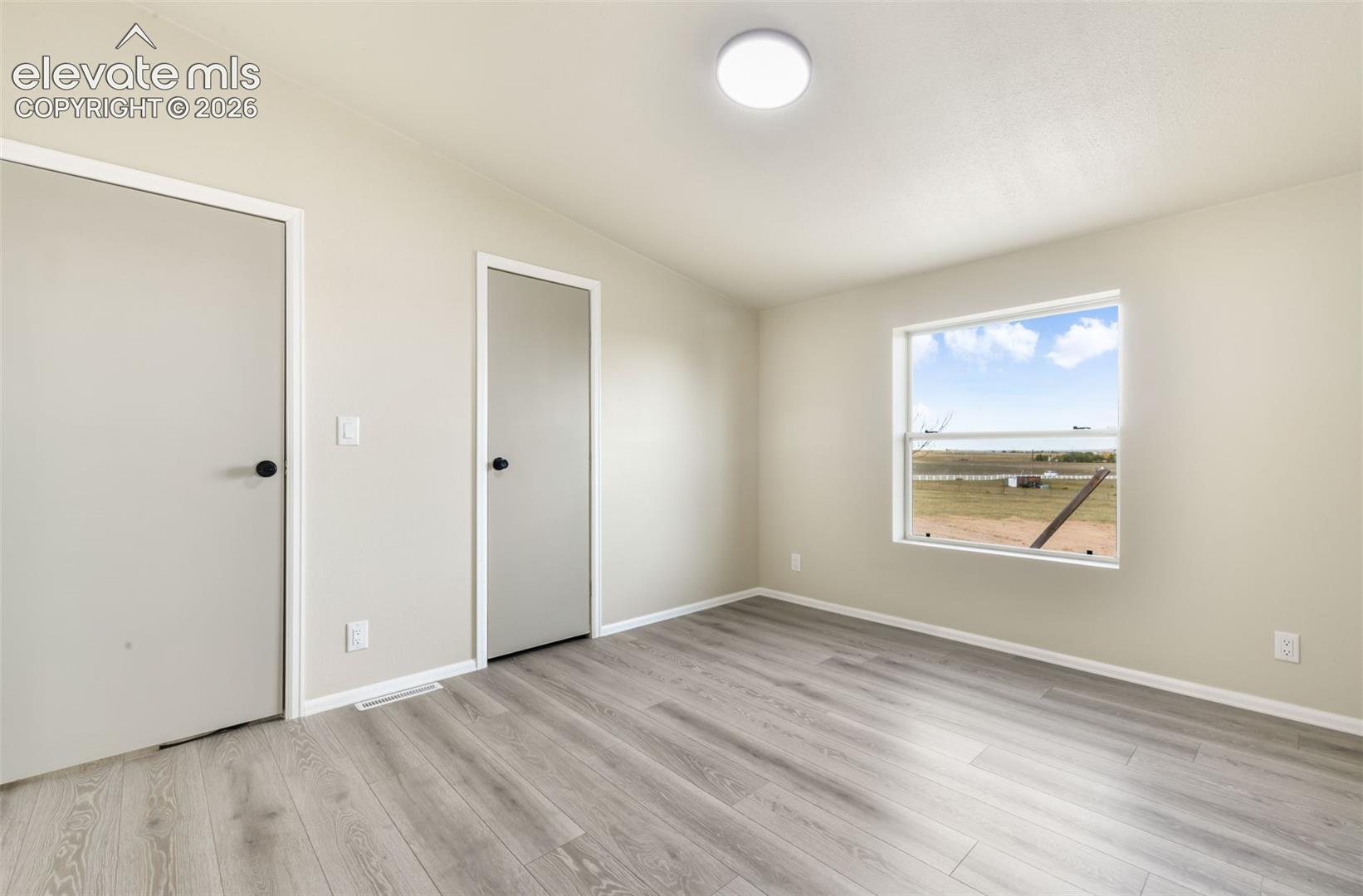 Light-filled interior with wood-finish flooring, neutral wall tones, and a flush-mount ceiling light