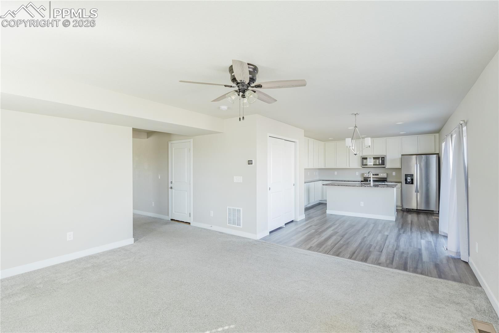 Unfurnished living room with a ceiling fan and light colored carpet