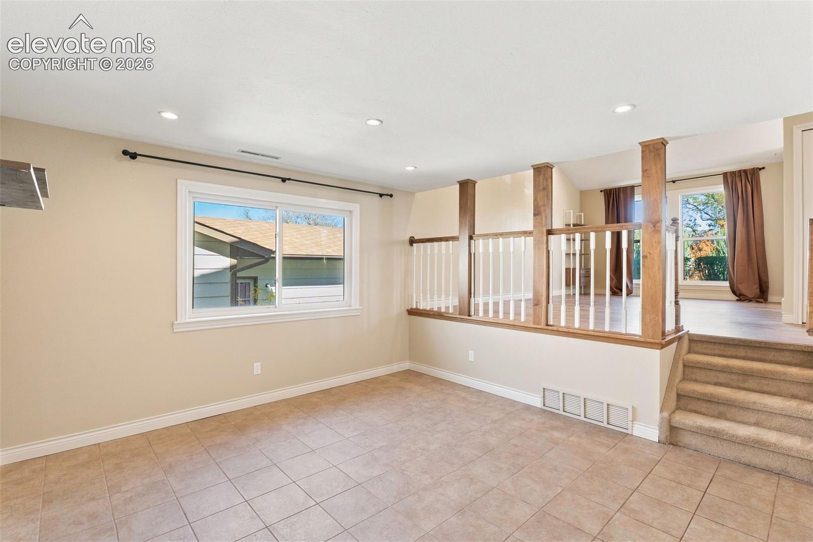Split-level interior featuring tile flooring, recessed lighting, carpeted stairs, and wood-toned railing with white balusters
