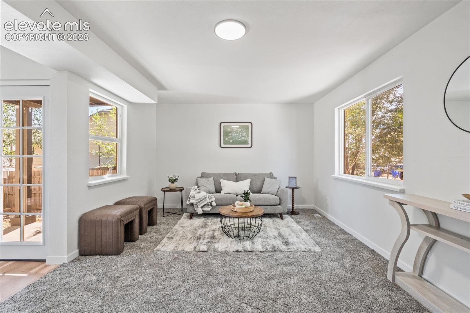 Neutral interior featuring wall-to-wall carpeting, expansive windows with natural light, and a multi-lite glass door