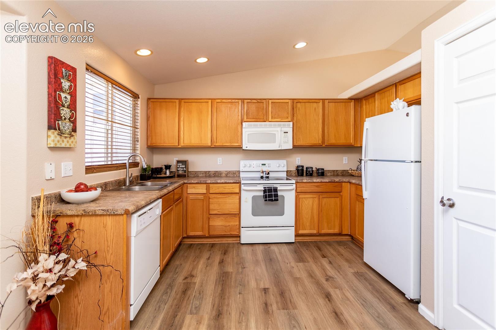 This kitchen combines classic natural wood cabinetry with resilient LVP flooring and recessed lighting