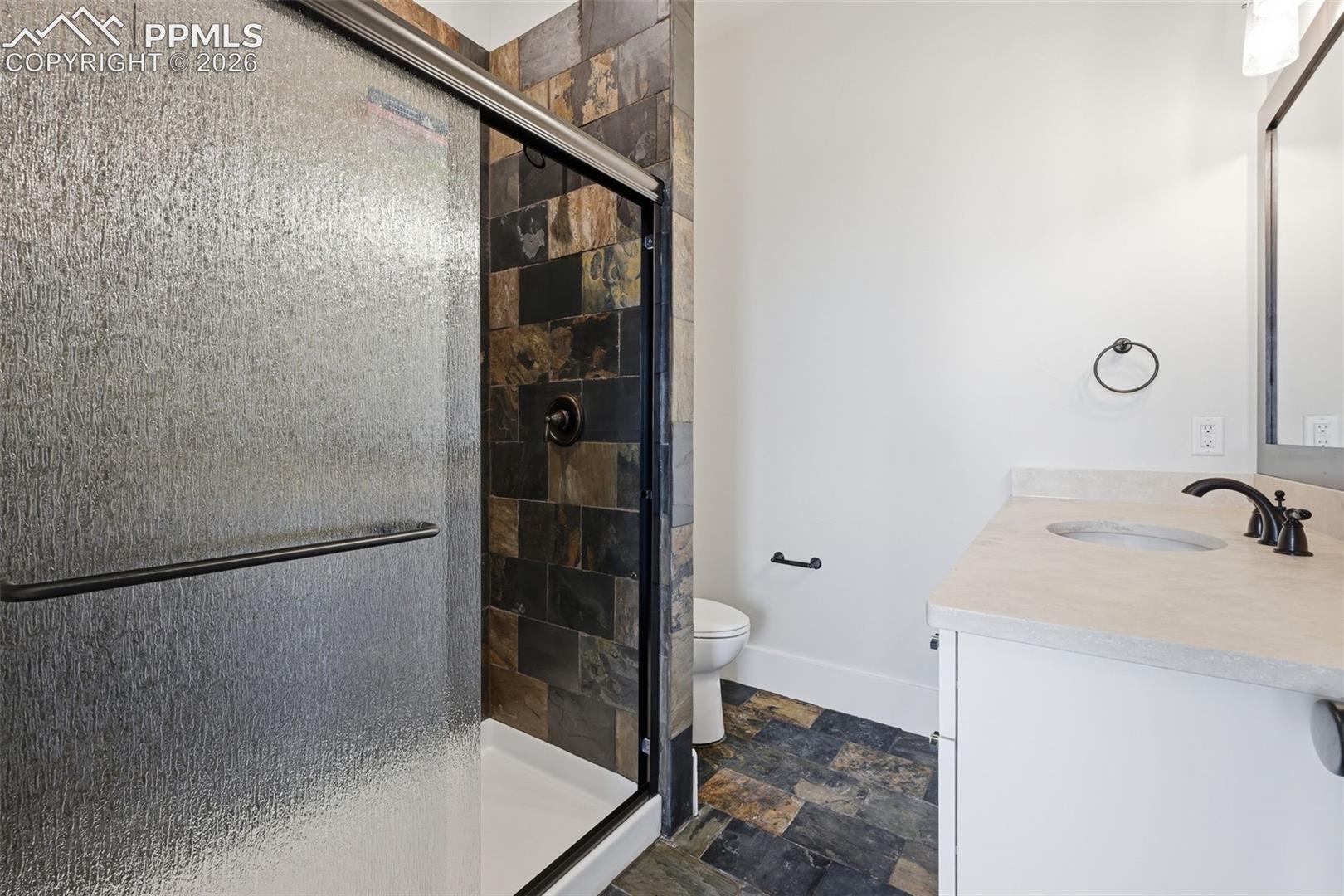 Bathroom featuring stone finish flooring, vanity, and a shower stall