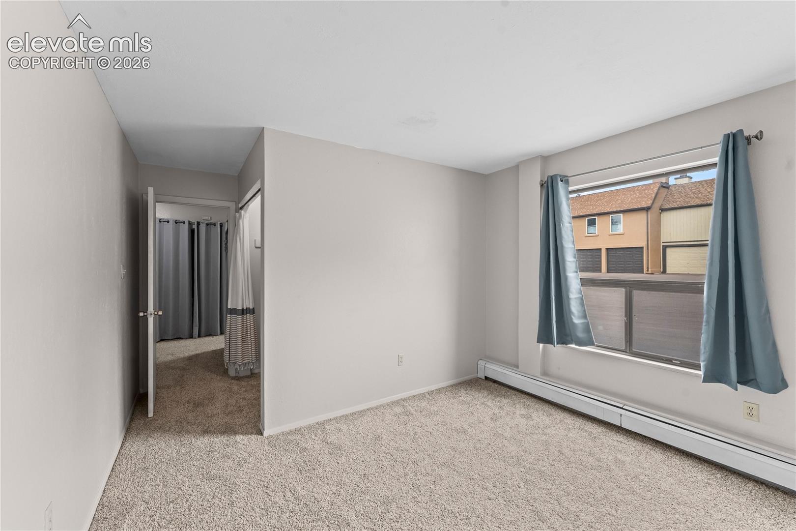 Neutral-toned interior room featuring wall-to-wall carpeting and a large window