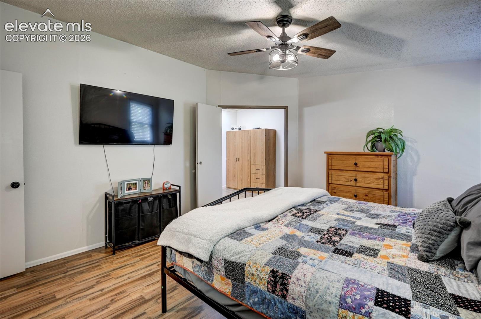 Bedroom with wood finished floors, a textured ceiling, and a ceiling fan
