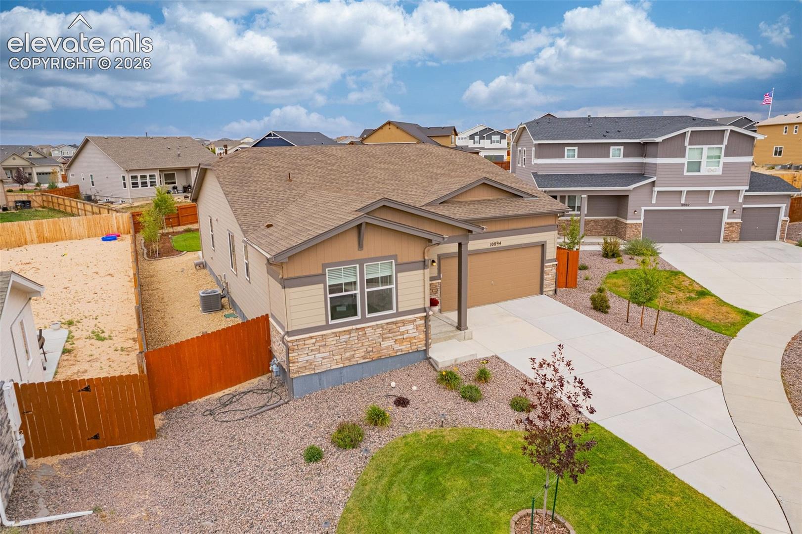 Single-story residence featuring a two-car garage, stone and siding exterior, and a concrete driveway