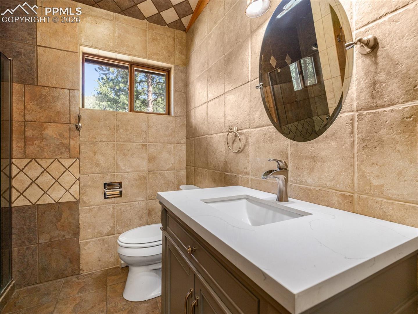 Full bath with vanity, tile walls, and a shower stall