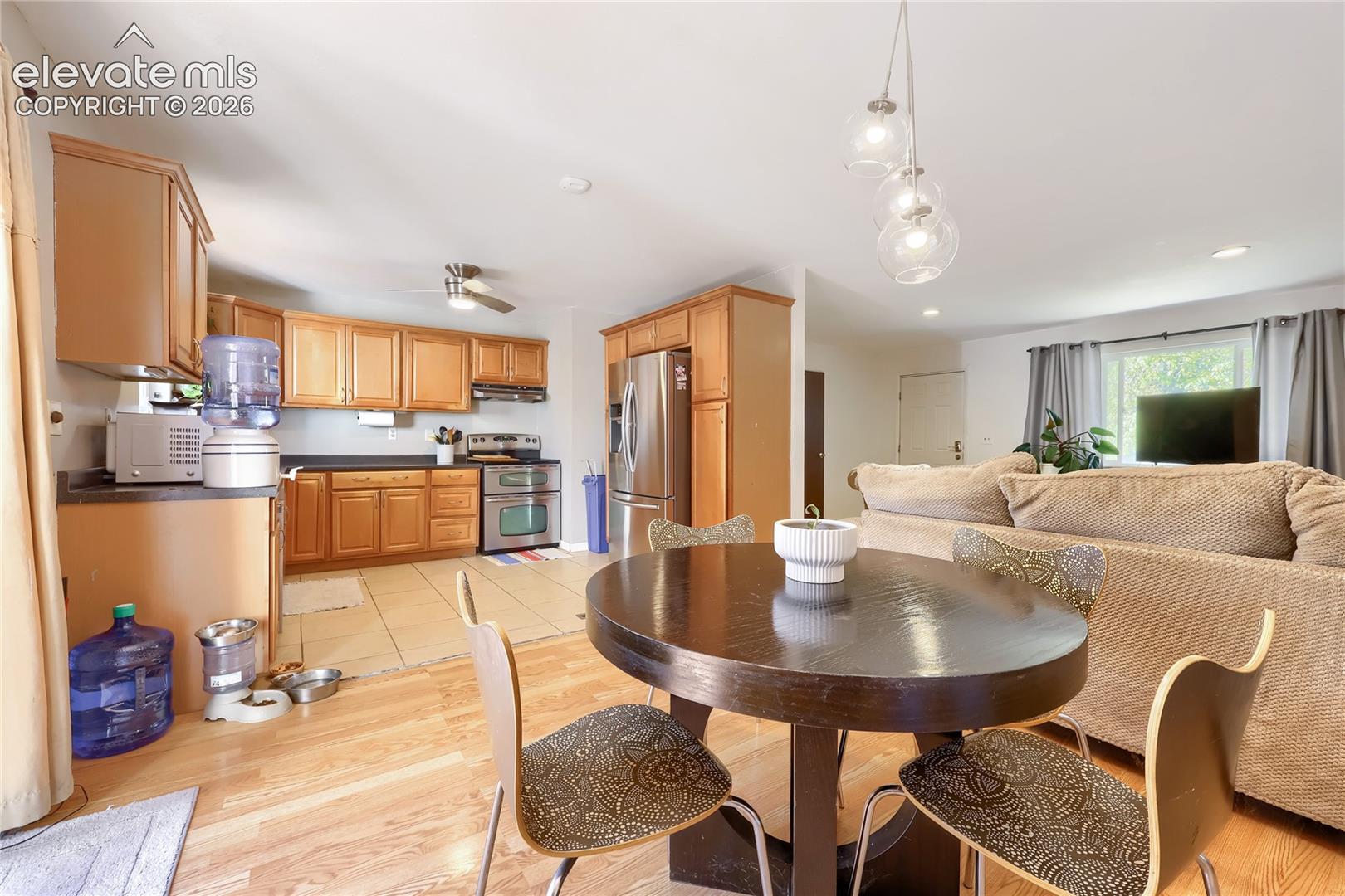 Kitchen featuring wood cabinetry, stainless steel appliances, tile flooring, and glass pendant lighting