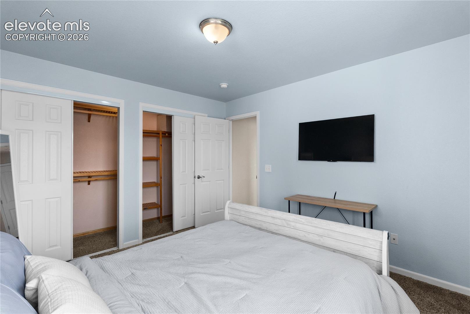Bedroom featuring a flush-mount ceiling light, light blue walls, and carpet flooring