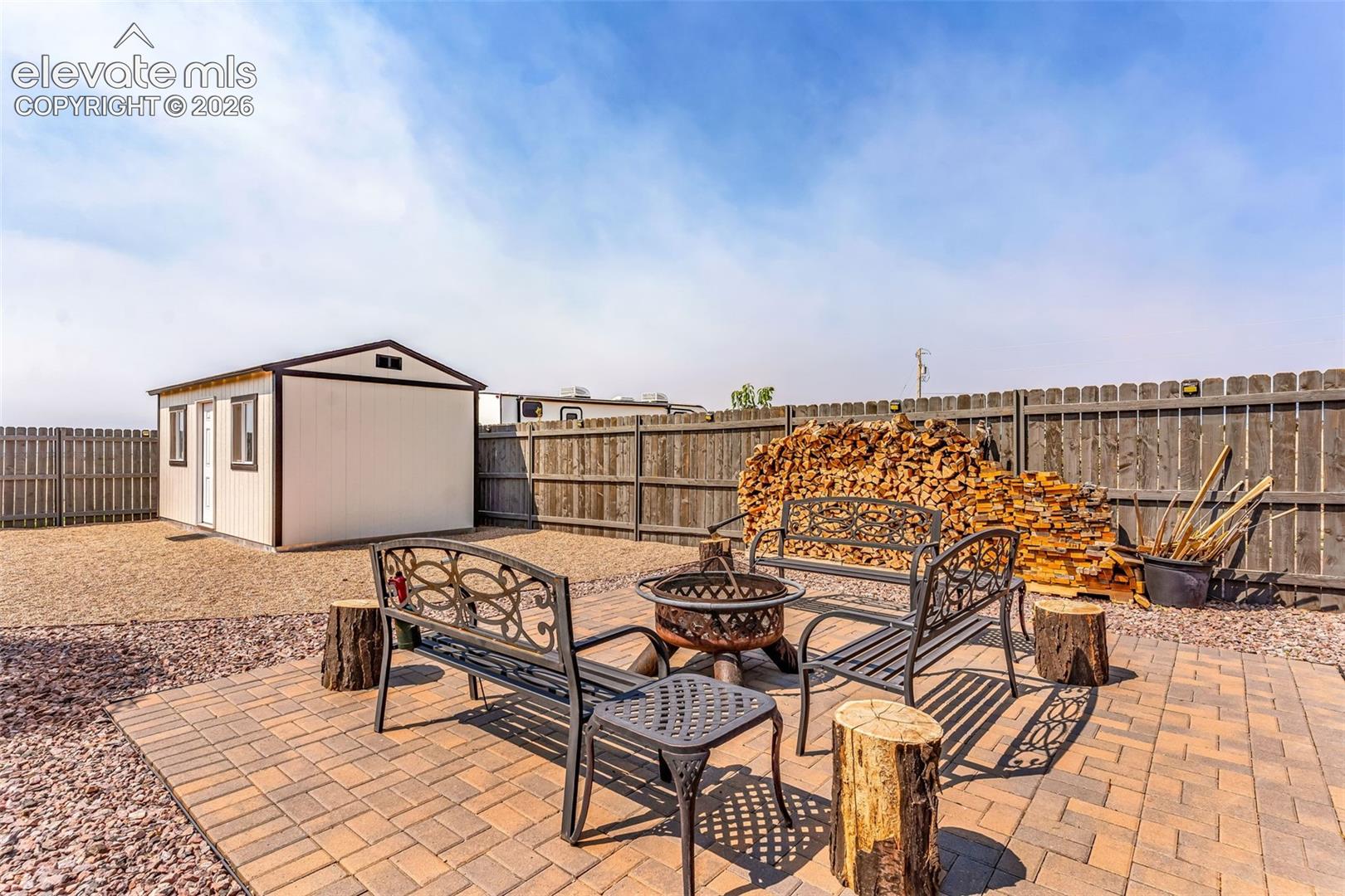 Patio area featuring paver flooring, a fire pit, and a detached storage shed