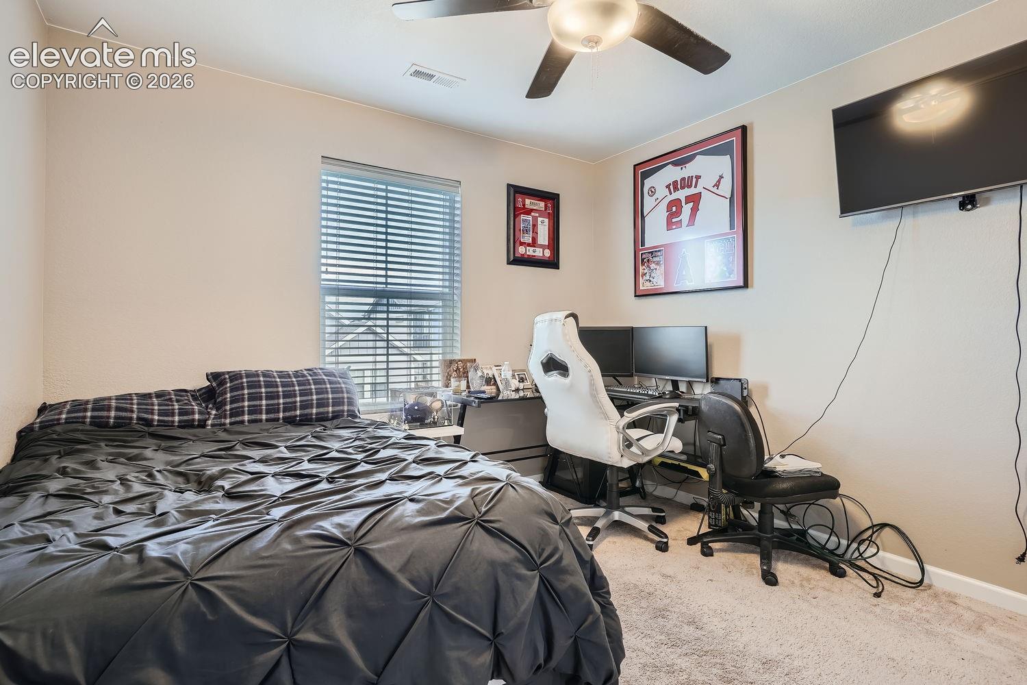 Neutral-toned room featuring wall-to-wall carpeting, a multi-blade ceiling fan with integrated lighting, and a single-pane window with horizontal blinds