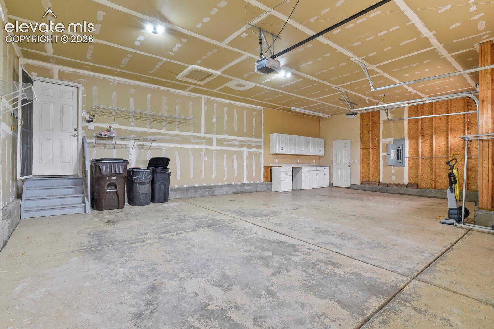 Spacious three-car garage featuring a concrete floor, built-in cabinetry with a countertop