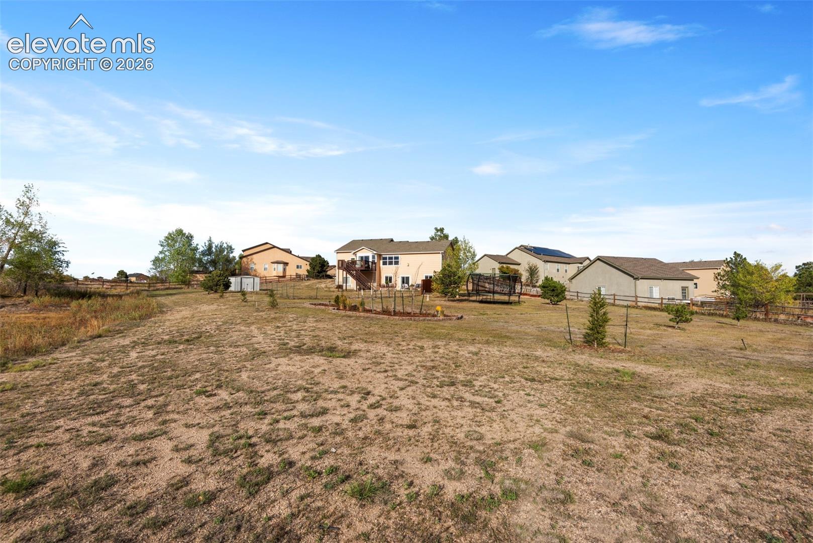 Expansive Lot Featuring an Elevated  Wood Deck, Perimeter Fencing, and Beautiful Established Landscaping