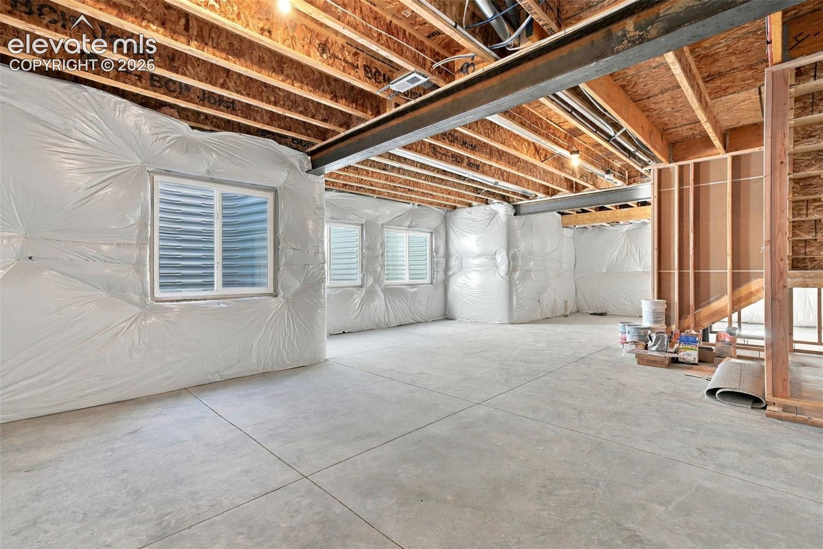 Unfinished basement with exposed ceiling joists, and concrete flooring