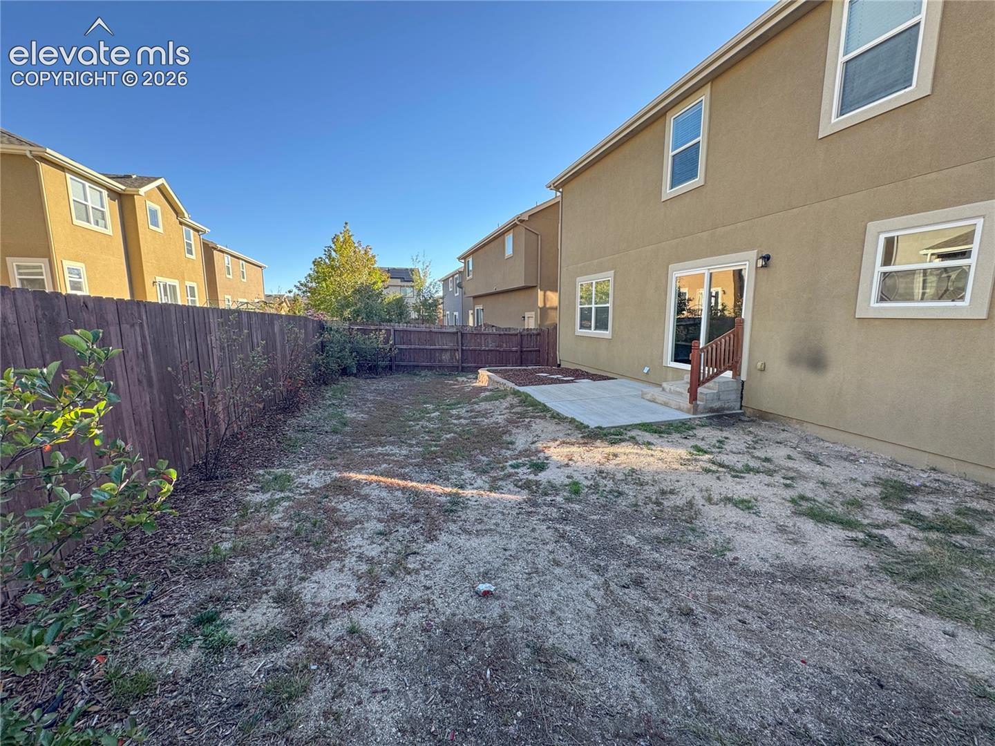 Rear exterior featuring a fenced yard, concrete patio, sliding glass door, and stucco siding