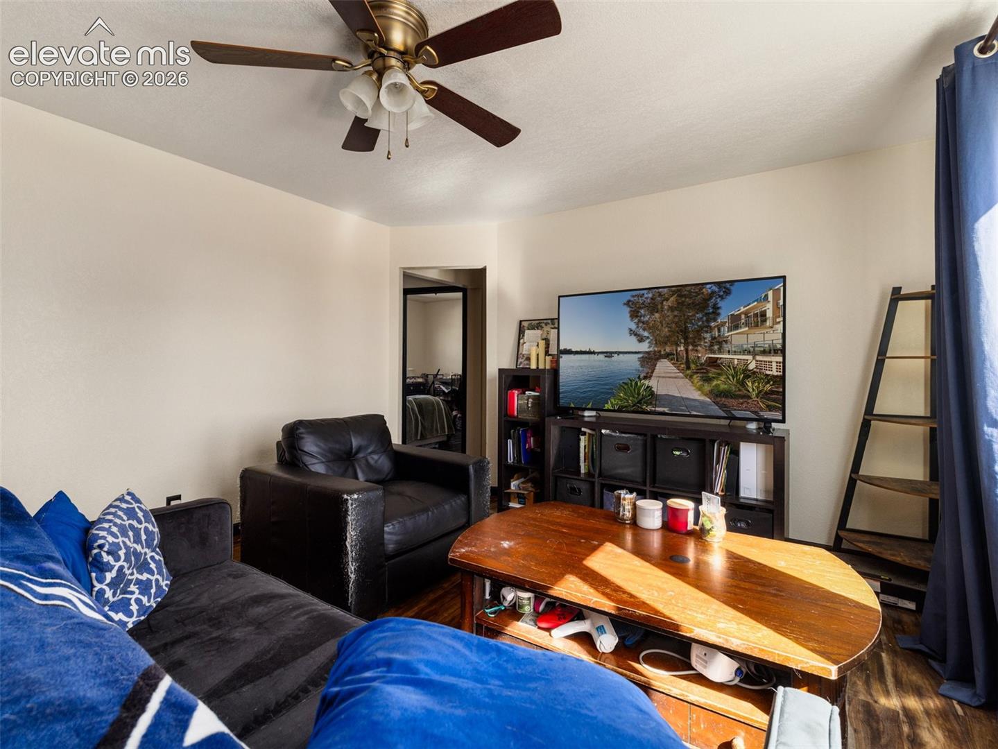 Ceiling fan with integrated lighting, wood-finish flooring, and neutral wall tones