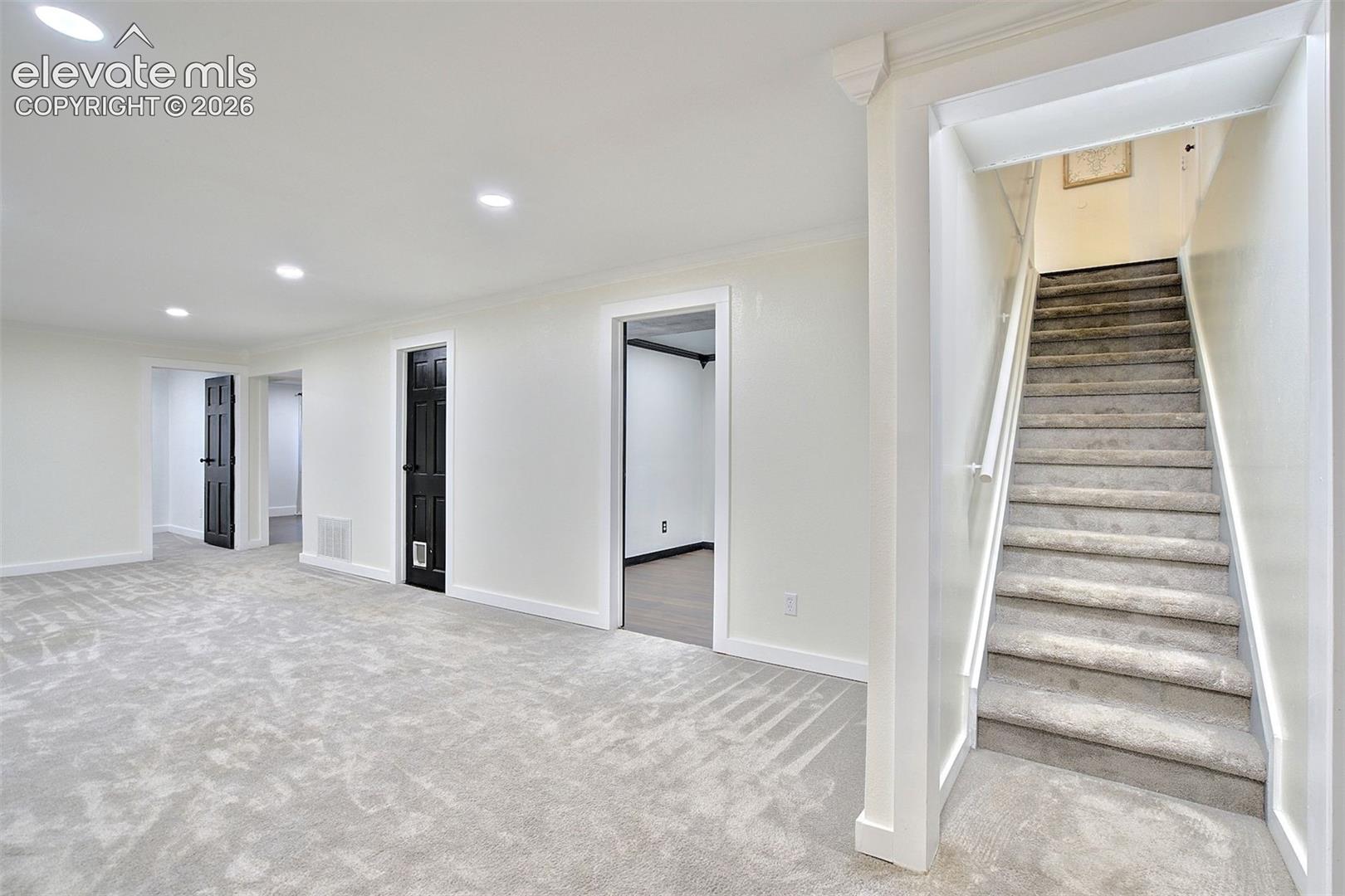 Interior space featuring neutral wall-to-wall carpeting, recessed ceiling lighting, crisp white trim, and high-contrast dark-finish interior doors