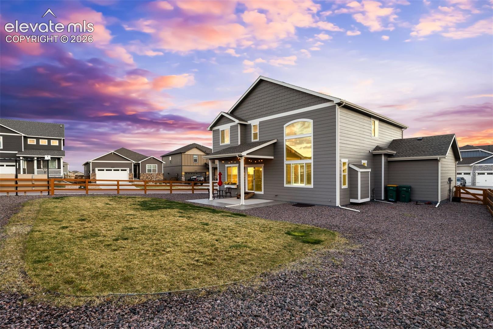 Gray siding exterior with white trim, large picture windows, covered patio, and a fenced yard