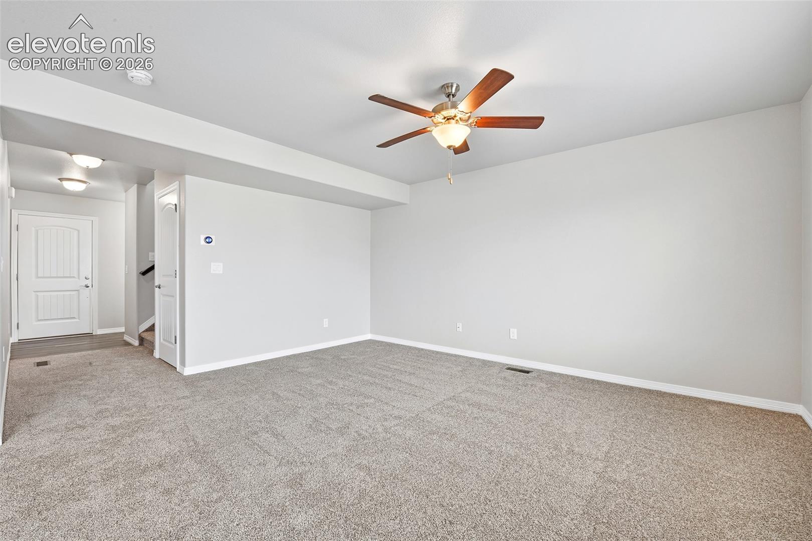 Neutral interior featuring wall-to-wall carpeting, a ceiling fan with integrated lighting, recessed lighting, and a paneled door