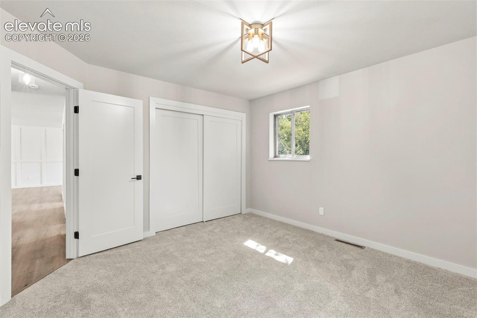 Carpeted room featuring white trim, and a gold-finish semi-flush mount light fixture