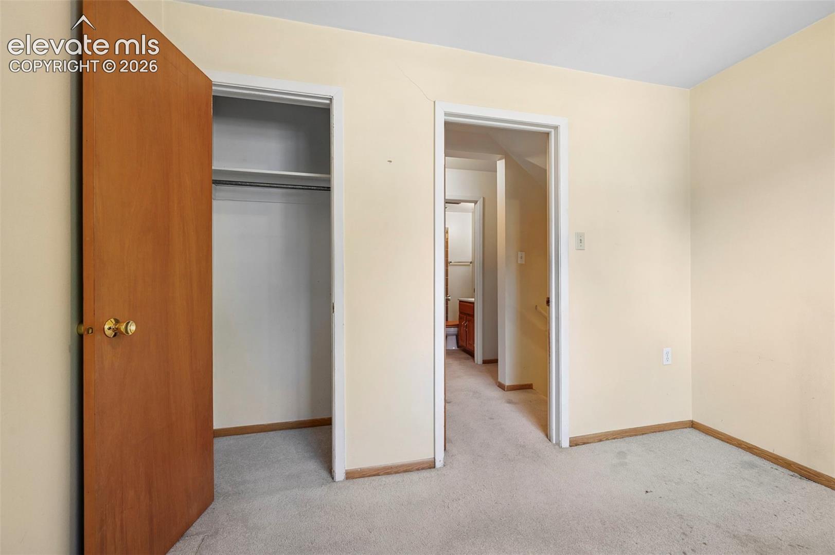 Bedroom 4 featuring neutral wall paint, carpeted flooring, and a built-in closet with shelving