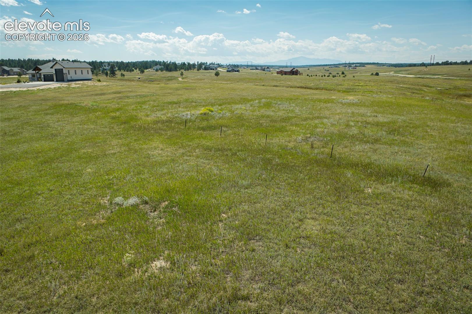 Expansive acreage featuring natural grasses, post-and-wire perimeter fencing, and distant mountain topography